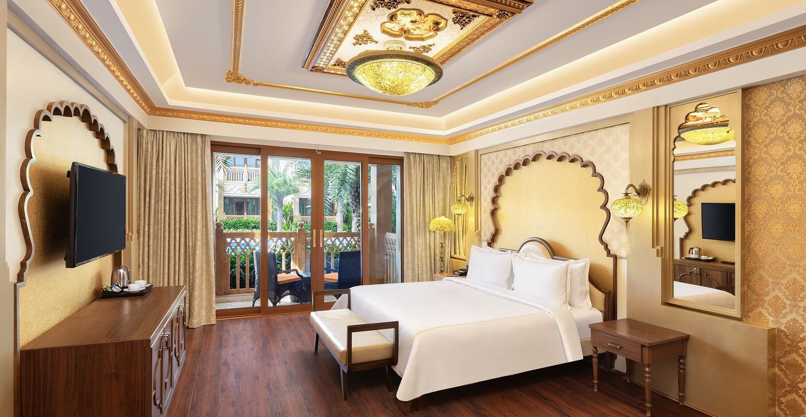 A full view of the room with royal decor that has a bed and a wall-mounted TV | Kaldan Samudhra Palace